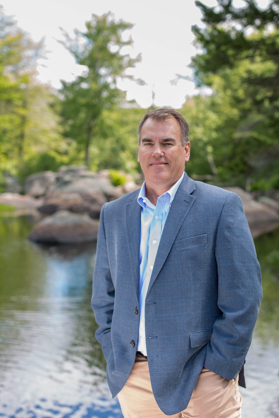 Man beside stream near forest Man standing outdoord near water